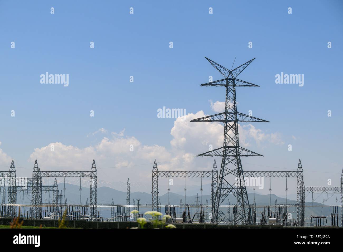 Hauteurs tours d'alimentation électrique en acier sous un ciel bleu clair. Équipement de sous-station électrique visible en arrière-plan Banque D'Images