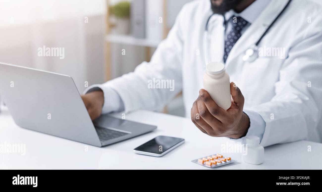 Médecin tenant bouteille avec des pilules, en utilisant un ordinateur portable Banque D'Images