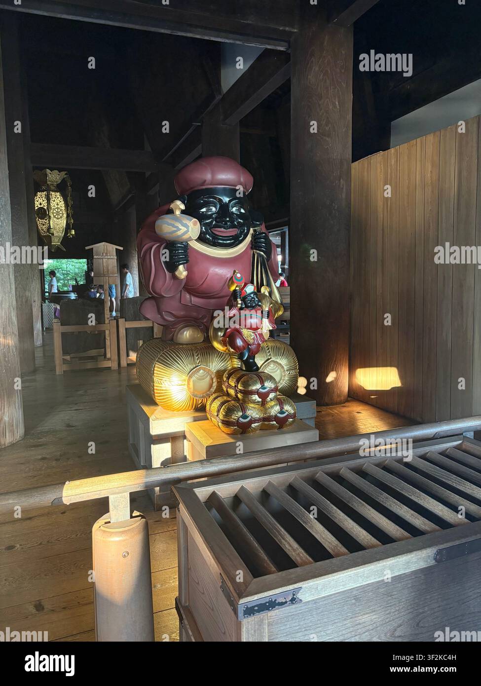 1er août 2025, Kyoto, Japon – Grande statue de déité Daikoku laquée avec des offrandes dorées exposées à l'intérieur d'une salle de sanctuaire shintoïste en bois traditionnel. - Image de stock capturée avec un smartphone