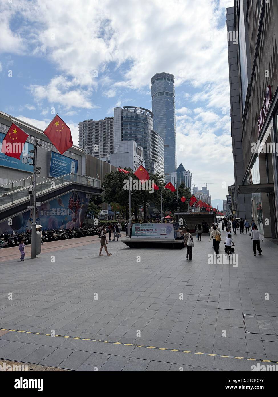 25 octobre 2025, district de Futian, Shenzhen, Chine – Place moderne du quartier des affaires bordée de drapeaux nationaux chinois, gratte-ciel et piétons dans le quartier financier de Shenzhen. - Image de stock capturée avec un smartphone