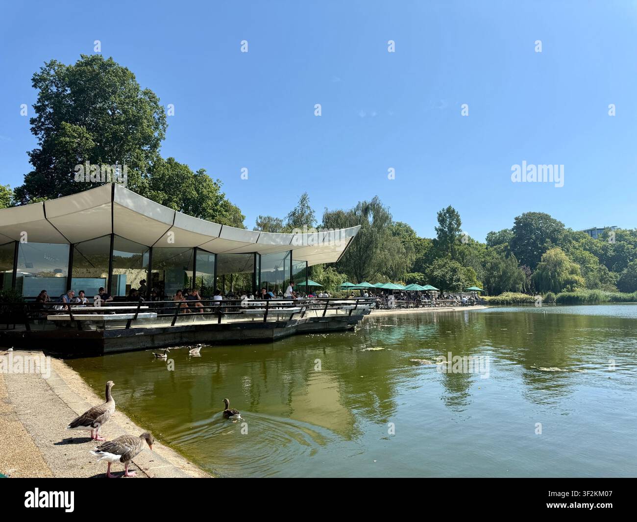 Le café Serpentine à Hyde Park à Londres par une journée ensoleillée d'été avec des gens mangeant sur la terrasse extérieure. Le lac et les canards au premier plan. Banque D'Images