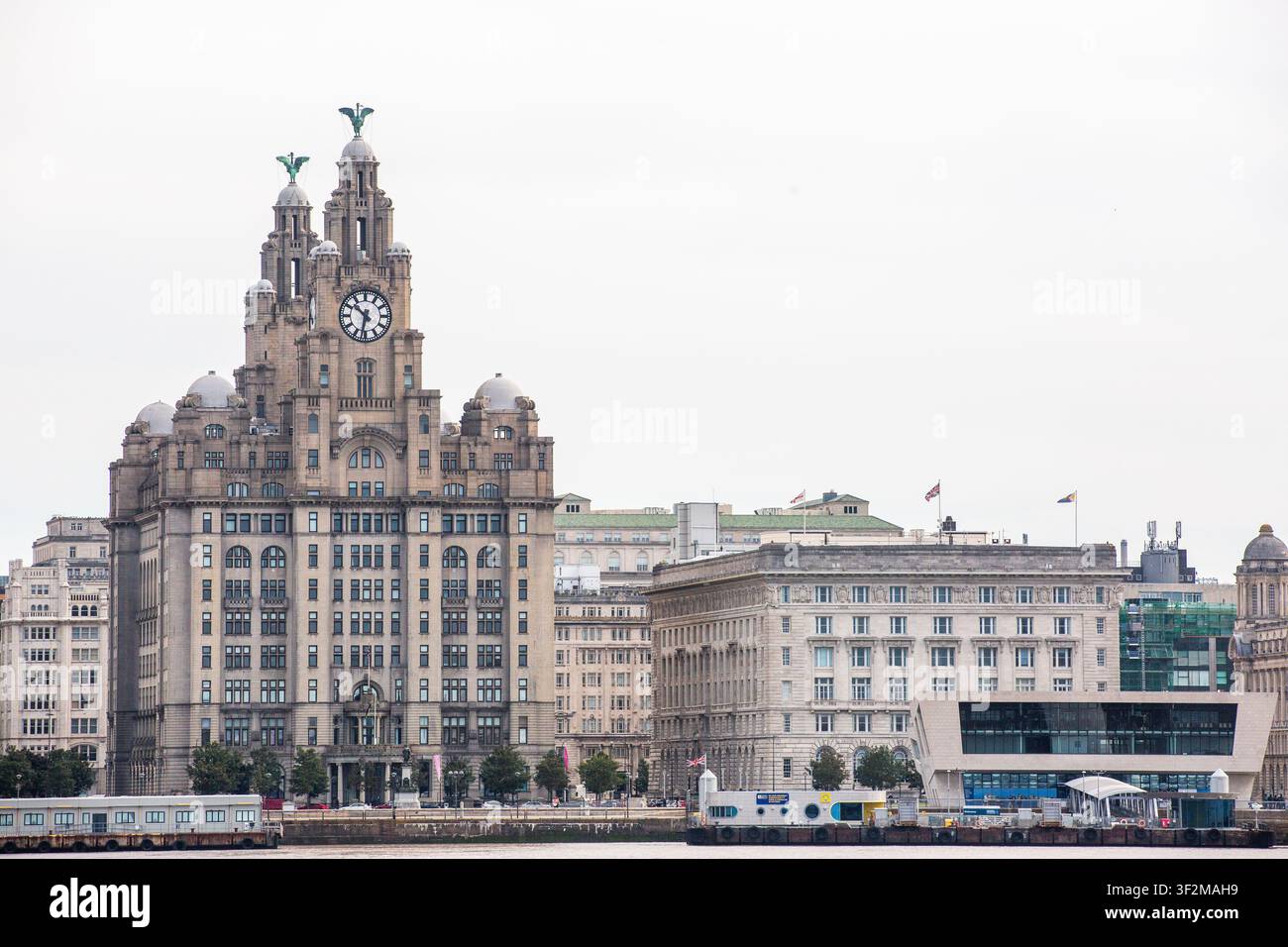 L'emblématique Liver Building se dresse fièrement contre un ciel pâle. La tour horloge historique domine le front de mer. Des bâtiments modernes se trouvent à côté de l'architecture ancienne. Pas de personnes Banque D'Images