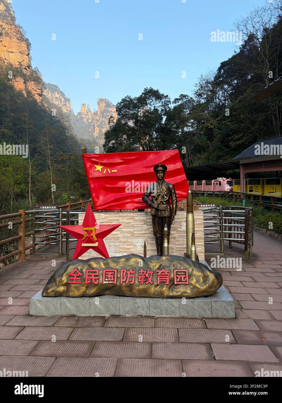 5 novembre 2025, Wulingyuan, Zhangjiajie, Chine – Statue en bronze d’un soldat avec le drapeau rouge de l’Armée populaire de libération et monument de la base d’éducation militaire patriotique chinoise au milieu du paysage karstique. Banque D'Images