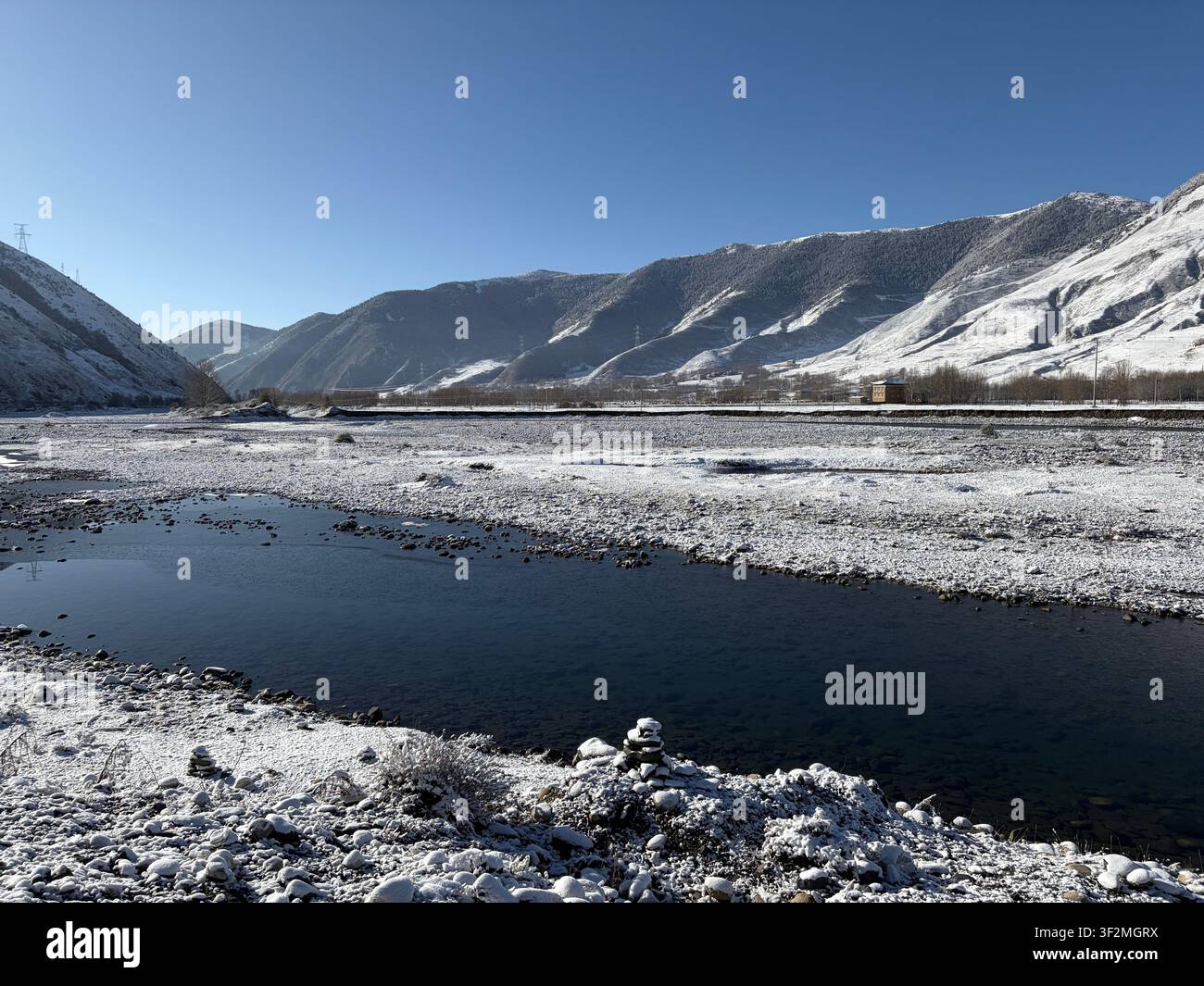 Rive rocheuse gelée avec des montagnes enneigées et un ciel bleu clair à Kangding, Préfecture autonome tibétaine de Kardze, Sichuan, Chine. Paysage hivernal de novembre. - Image de stock capturée avec un smartphone