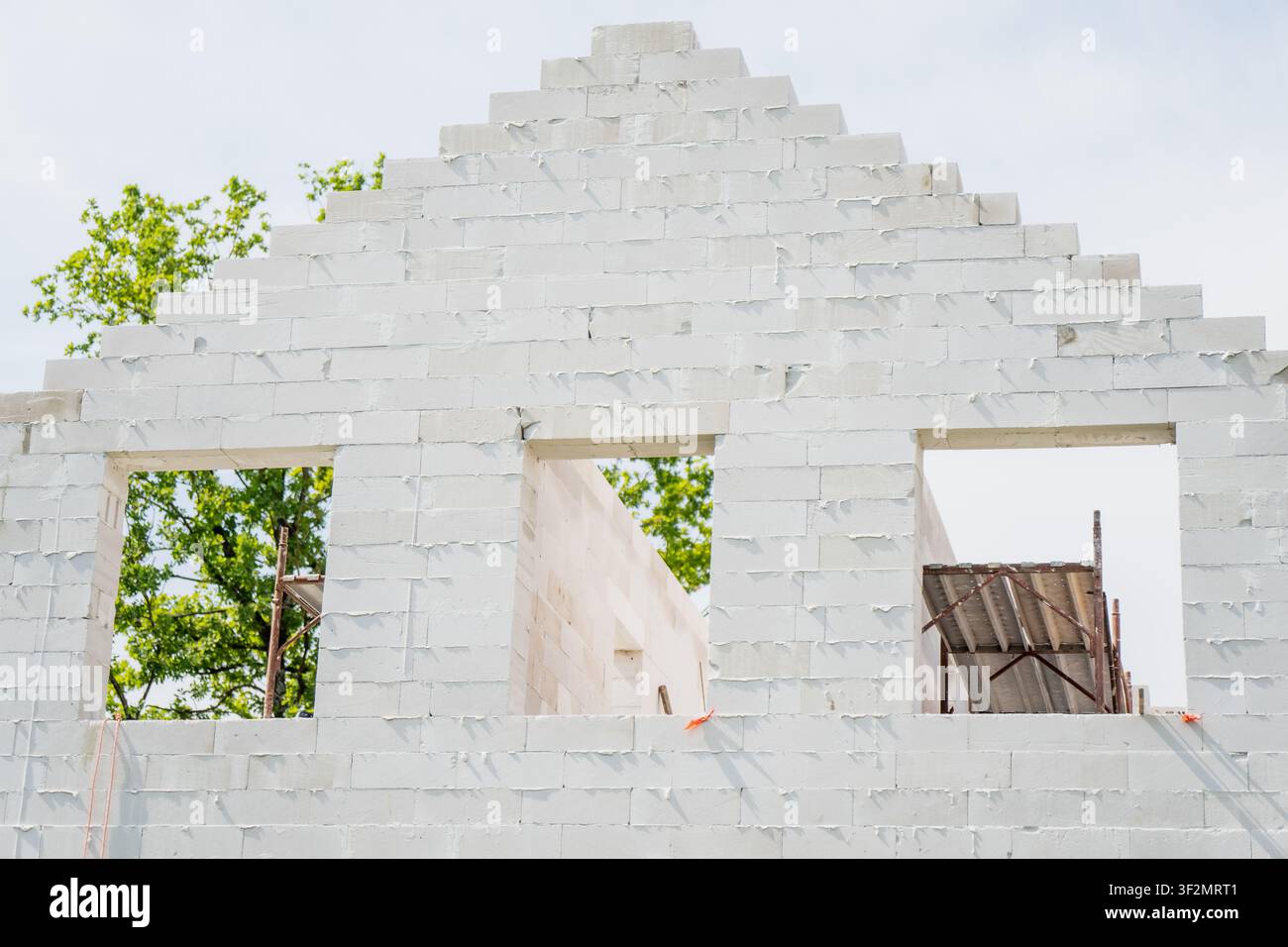 Blocage de béton alvéolaire formant une structure de mur à pignon échelonné sur un chantier de construction résidentielle, représentant l'artisanat de la maçonnerie et l'ingénierie Banque D'Images