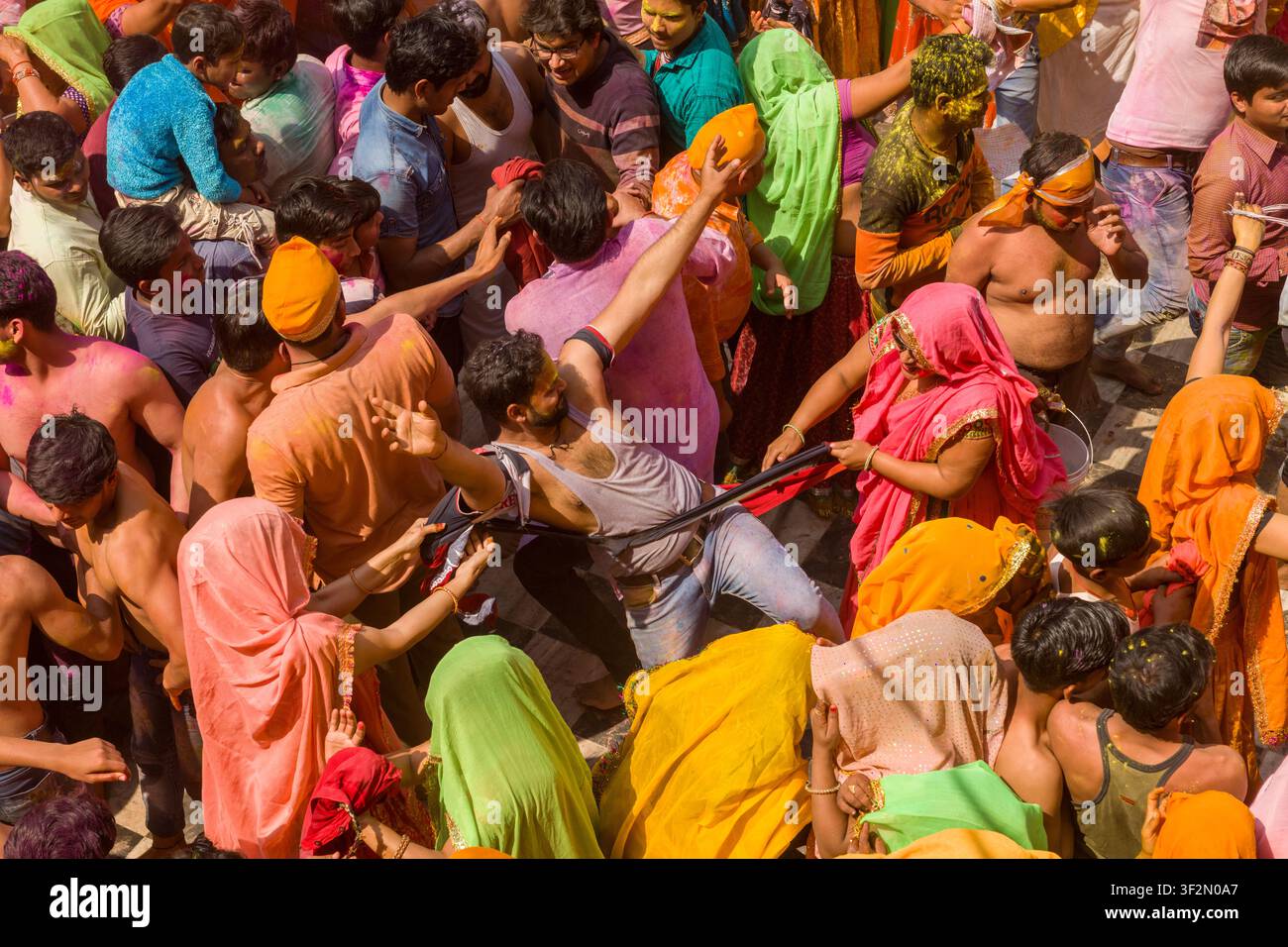 Regard vers le bas sur des femmes vêtues de saris qui arrachent la chemise d'un homme au début du Dauji Huranga, dans la cour du Shri Dauji Maharaj Mandir, dans le village de Baldev près de Mathura, Uttar Pradesh, Inde. Banque D'Images