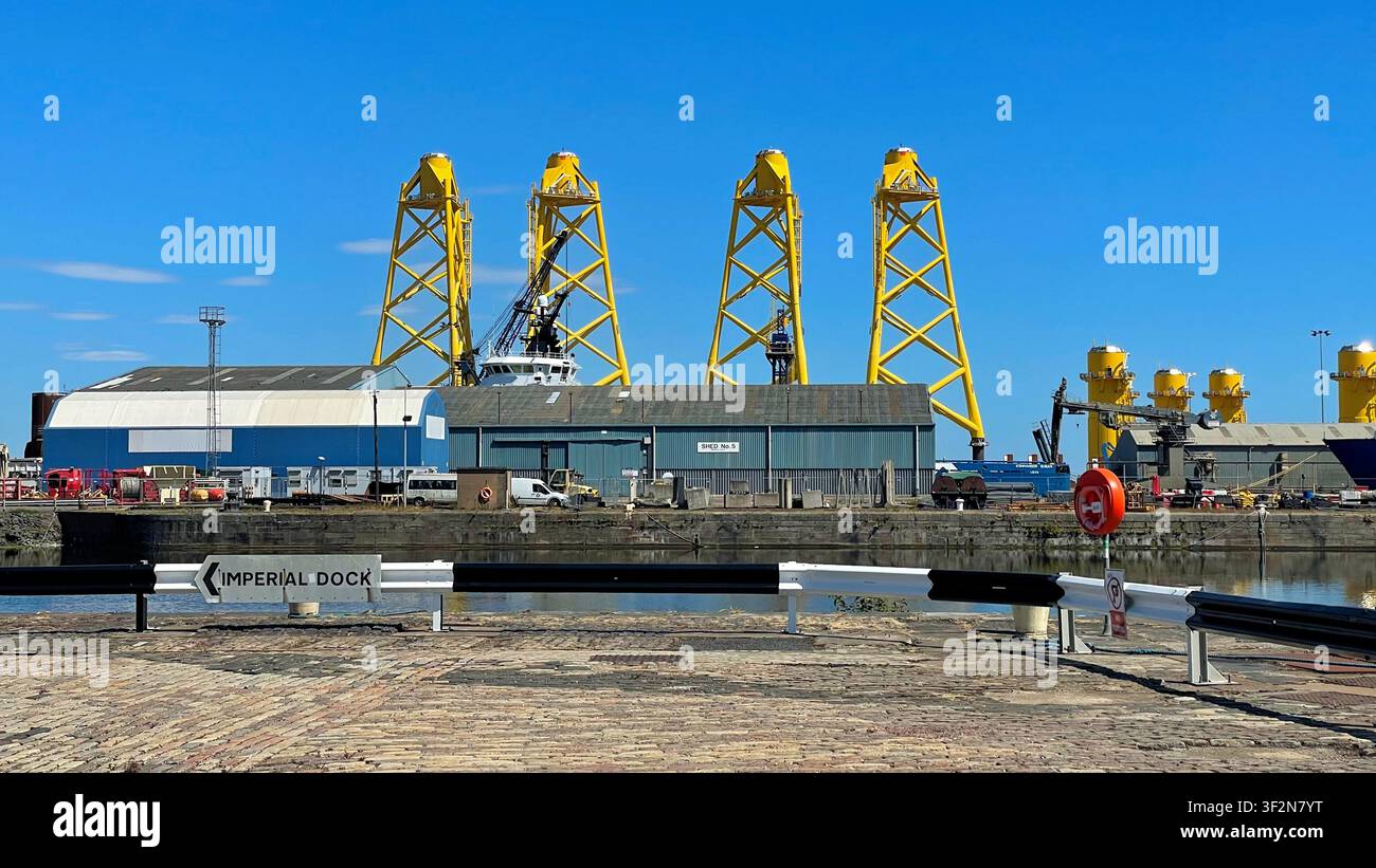 Structures de tours treillis à trois pieds jaunes connues sous le nom de fondations « jacket » étant fabriquées pour un projet éolien offshore, quais de Leith à Édimbourg, Écosse - Image de stock capturée avec un smartphone