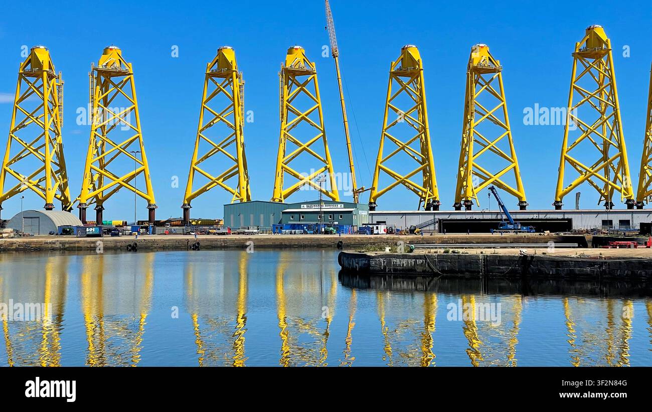 Structures de tours treillis à trois pieds jaunes connues sous le nom de fondations « jacket » étant fabriquées pour un projet éolien offshore, quais de Leith à Édimbourg, Écosse Banque D'Images