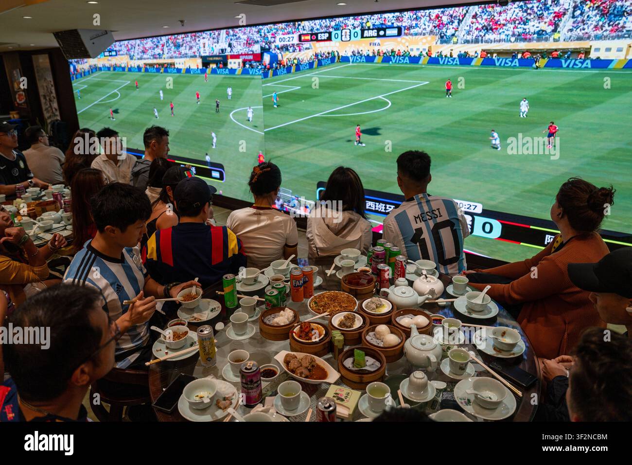 Des fans regardent la finale de la Coupe du Monde en mangeant du dim sum au Lin Heung Lau, le restaurant de dim sum qui propose une diffusion en direct de la Coupe du Monde tout en servant du dim sum traditionnel aux fans à Hong Kong, le 20 juillet 2026. NEXPHER/Vernon Yuen Banque D'Images