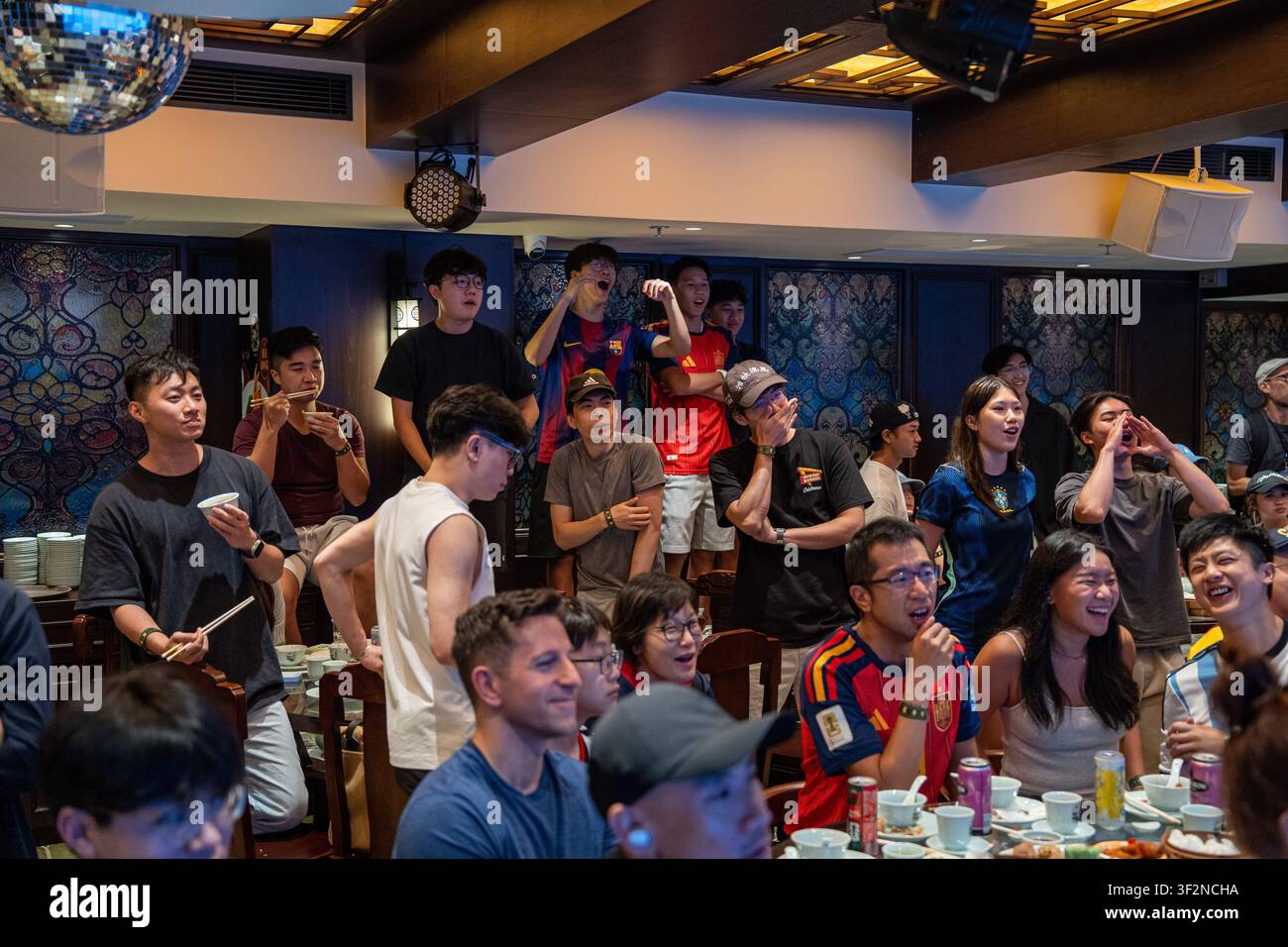 Des fans regardent la finale de la Coupe du Monde en mangeant du dim sum au Lin Heung Lau, le restaurant de dim sum qui propose une diffusion en direct de la Coupe du Monde tout en servant du dim sum traditionnel aux fans à Hong Kong, le 20 juillet 2026. NEXPHER/Vernon Yuen Banque D'Images
