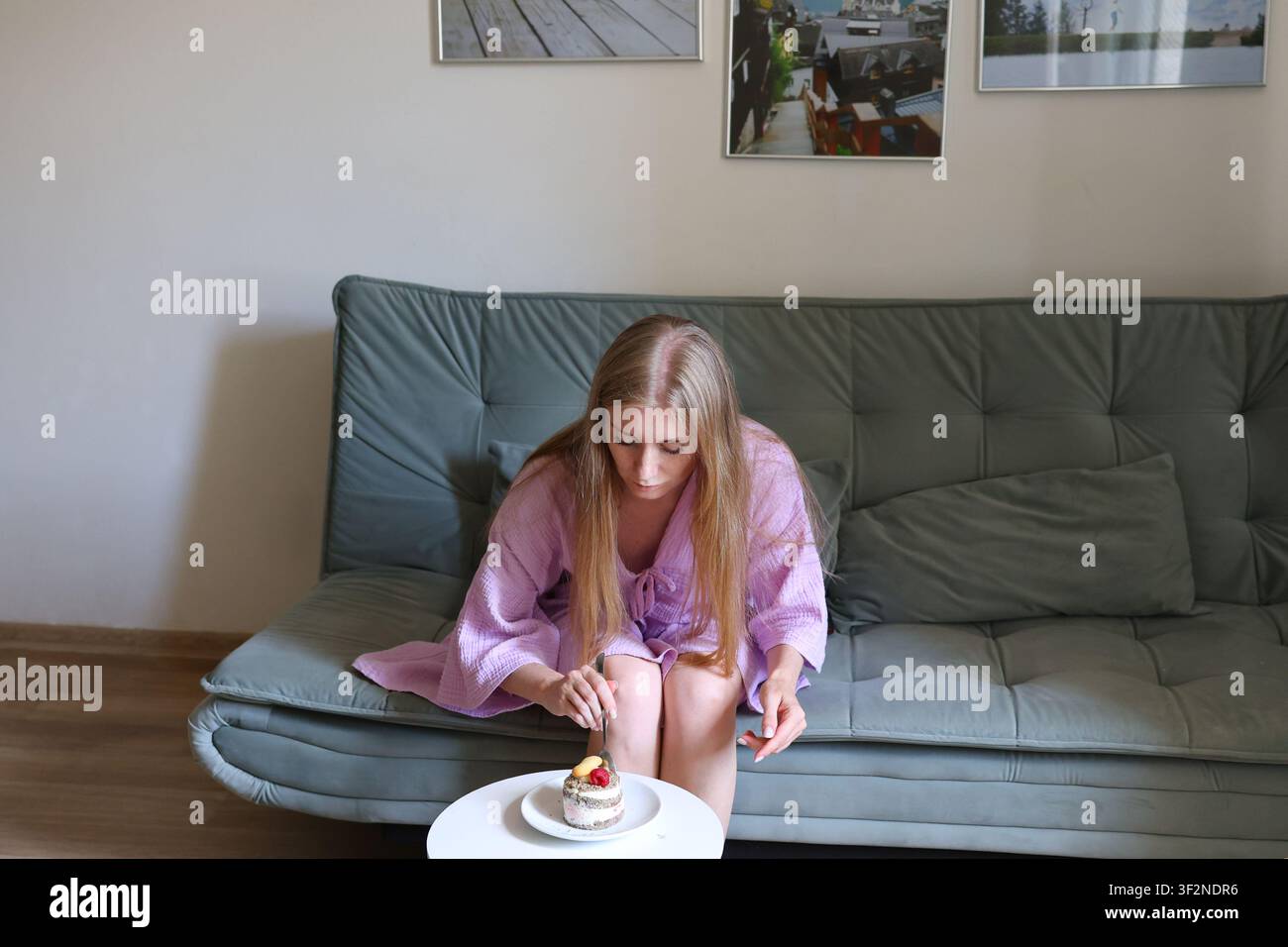 Jeune femme savourant un petit dessert à la maison, promouvant une alimentation équilibrée, une indulgence consciente et un mode de vie sain. Banque D'Images