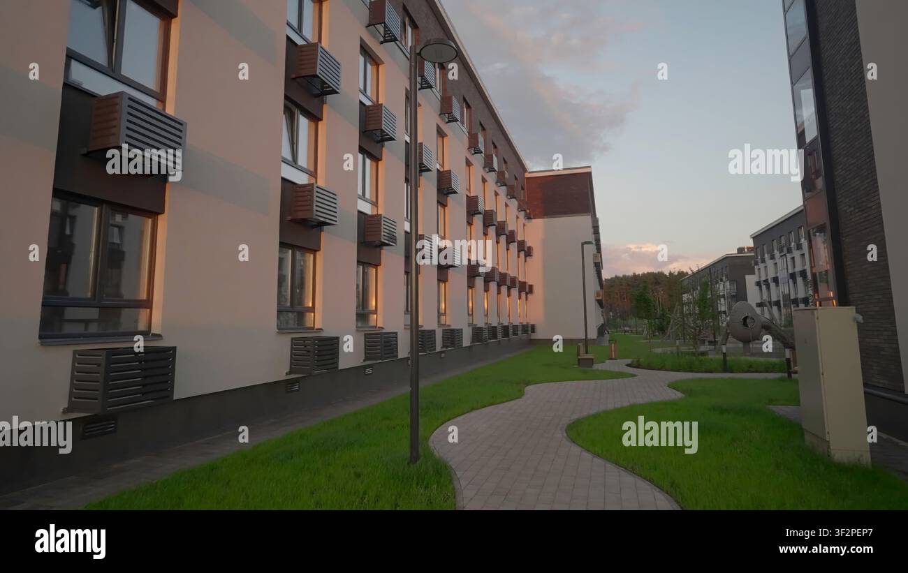 Chemin ensoleillé dans une cour paisible. Scène extérieure sereine mettant en vedette des fenêtres lumineuses et une végétation luxuriante. Clip d'archive Banque D'Images