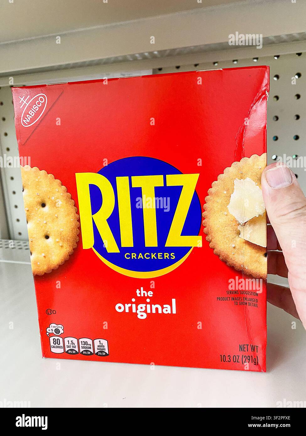 Une personne tenant une boîte rouge de crackers Nabisco Ritz The Original sur une étagère blanche d'un magasin. - 17 juillet 2026 Puyallup WA, États-Unis Banque D'Images