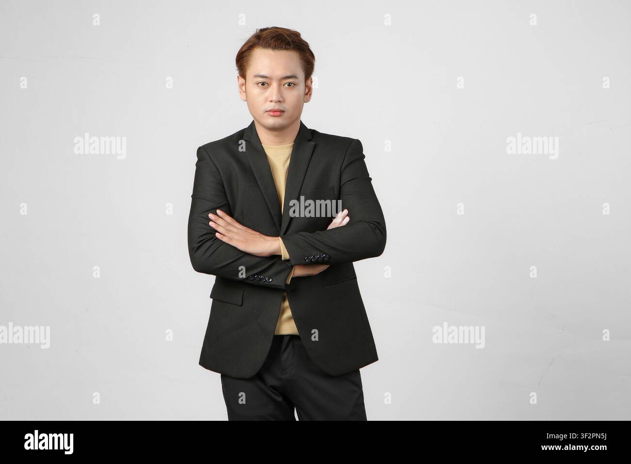 Portrait d'un homme d'affaires asiatique heureux portant un costume avec les bras croisés sur un fond isolé Banque D'Images