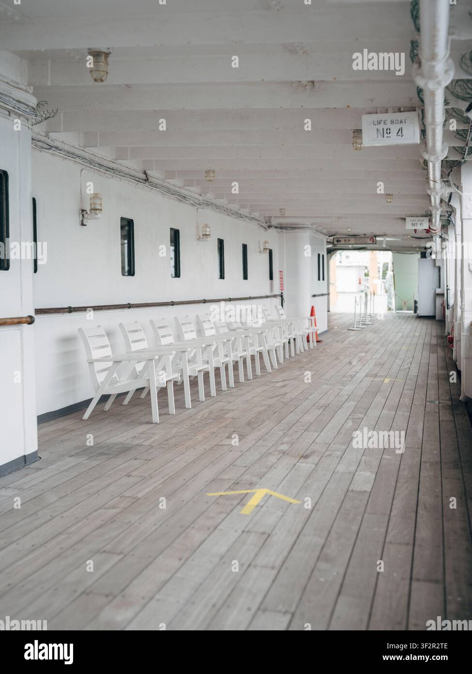 Range de chaises longues en bois blanc le long du pont-promenade couvert du paquebot Hikawa Maru Banque D'Images
