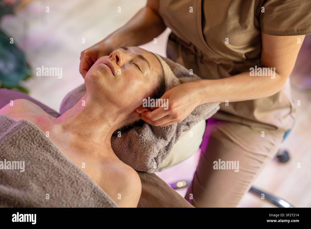 Femme tranquille sur une table de spa recevant un traitement de soins de la peau et une procédure de massage thérapeutique dans un salon. Banque D'Images