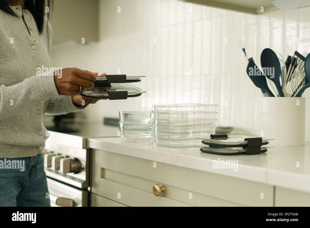 Femme organisant des contenants alimentaires en verre dans la cuisine Banque D'Images