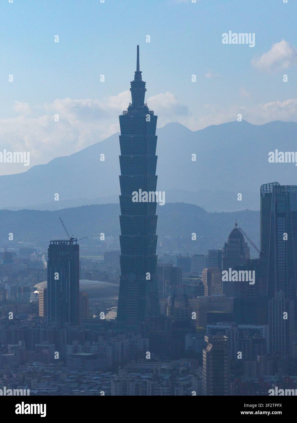 Vue aérienne du gratte-ciel Taipei 101 s'élevant au-dessus de la skyline urbaine de la ville de Taipei avec des montagnes au loin sous un ciel bleu clair, Taipei City, Taïwan. Banque D'Images