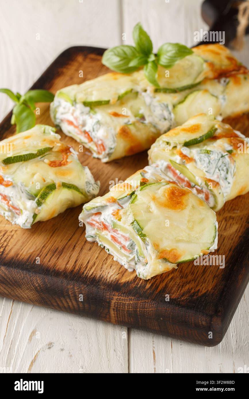 Rouleau de courgettes au fromage frais et saumon, gros plan sur la planche en bois sur la table. Vertical Banque D'Images