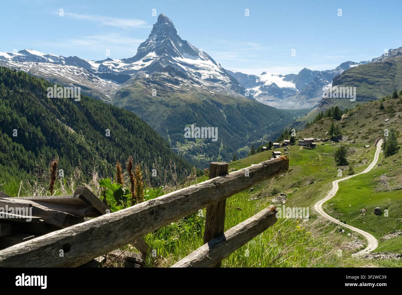 Paysage des Alpes suisses mettant en vedette le pic du Matterhorn, des pâturages vallonnés verdoyants, une route sinueuse et des chalets traditionnels Banque D'Images