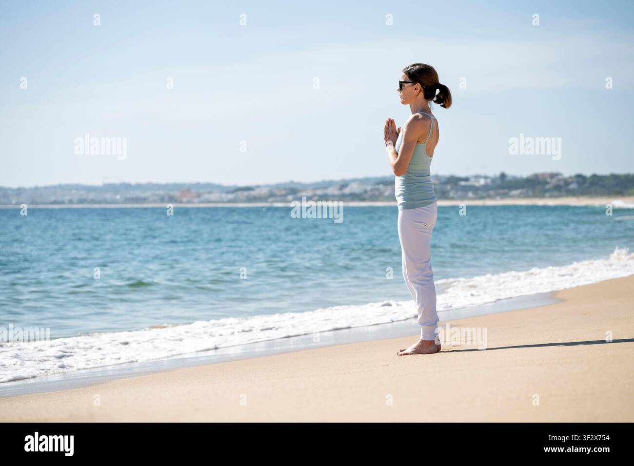 Femme pratiquant la méditation yoga sur une plage ensoleillée Banque D'Images