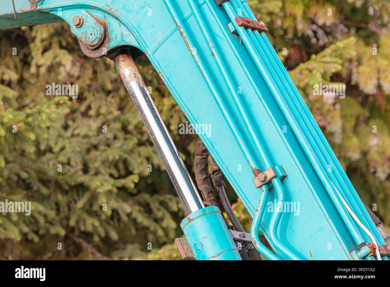 Cylindres hydrauliques et tuyaux sur une machine excavatrice bleue, montrant la puissance et un contrôle précis pour les travaux de construction en extérieur Banque D'Images
