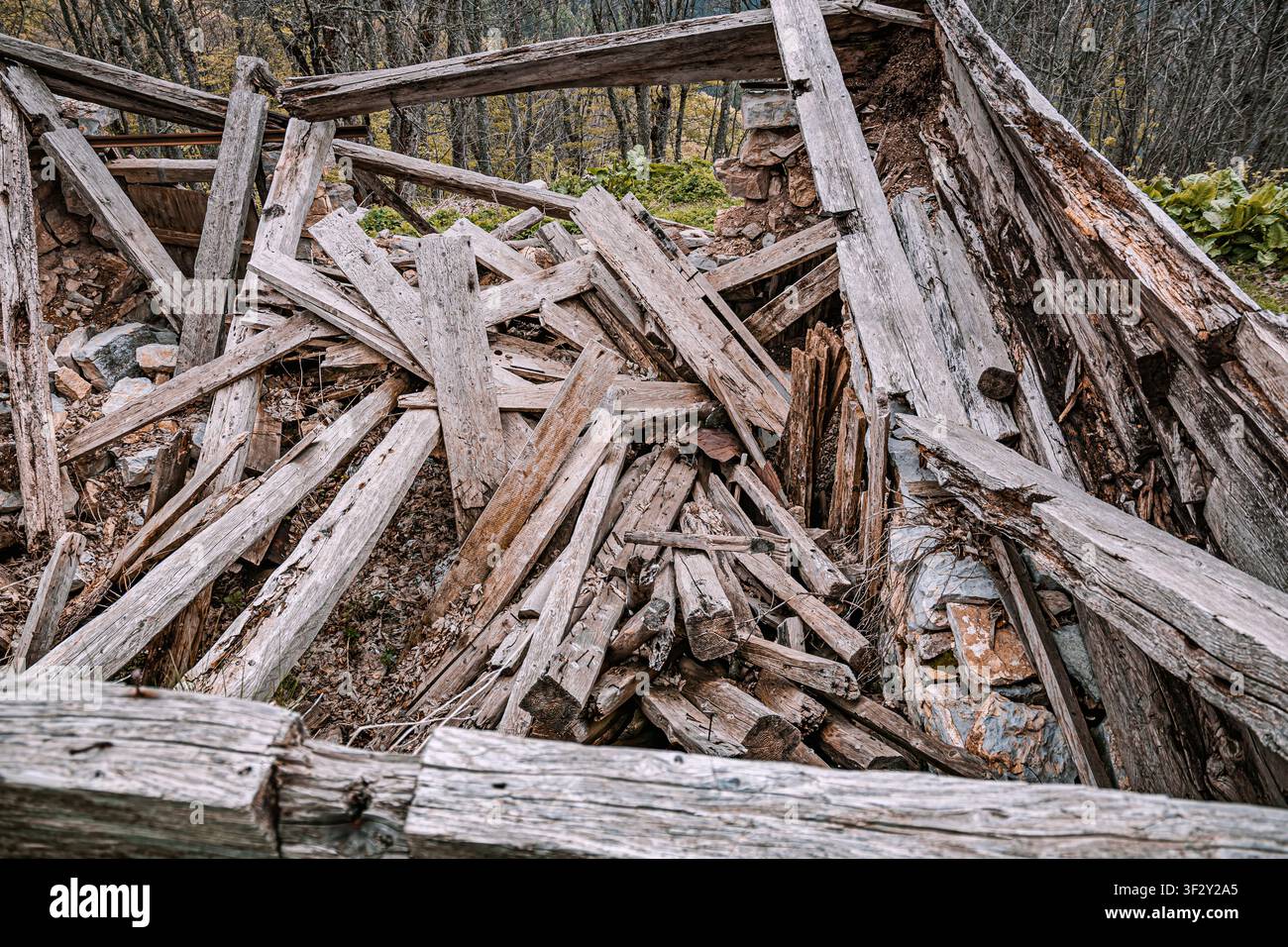 Ancienne maison abandonnée s'effondrant en un tas de débris de bois pourrissants et de murs de pierre, montrant la destruction et la négligence Banque D'Images