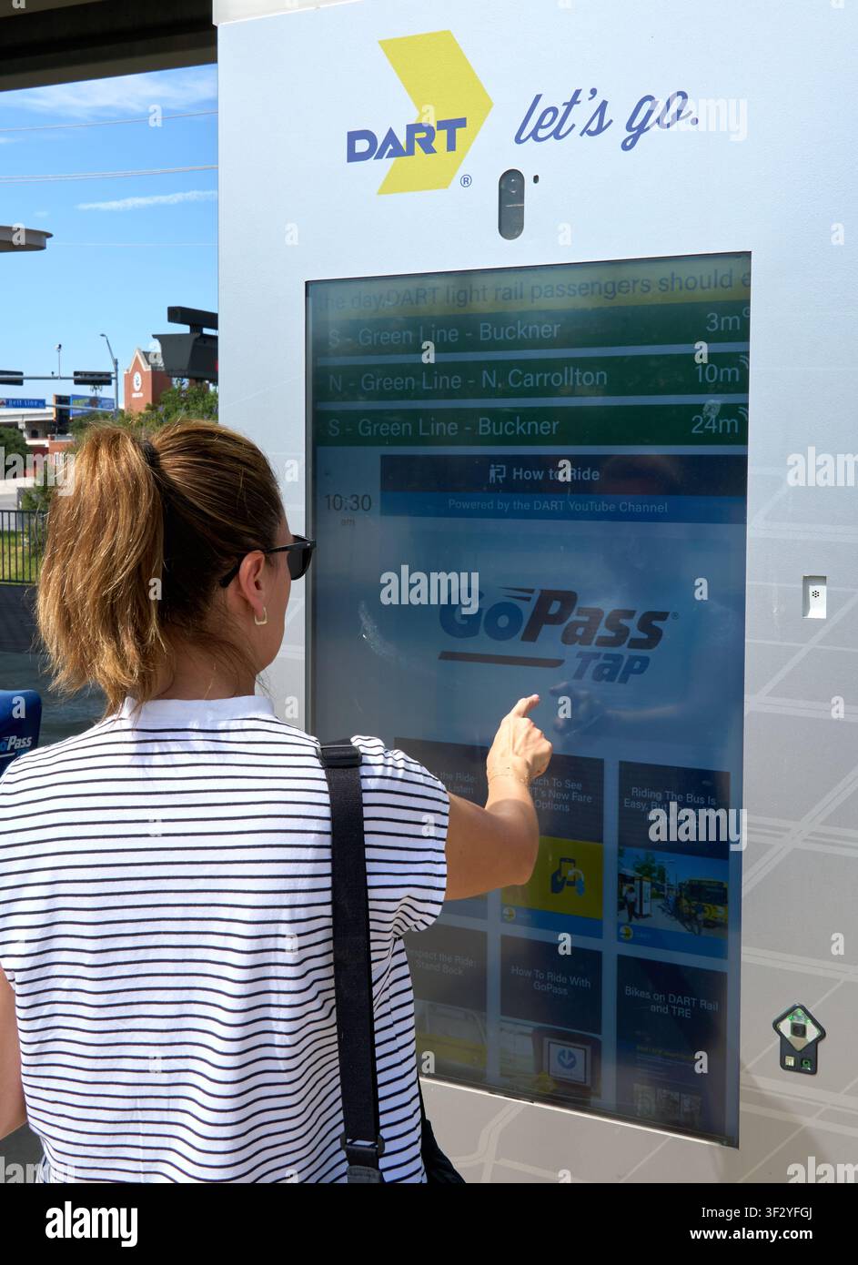 DALLAS, TX, USA - 11 JUILLET 2026 : Une femme interagit avec un écran tactile DART dans une station à Dallas, Texas, vérifiant les horaires des tramways. DART Banque D'Images