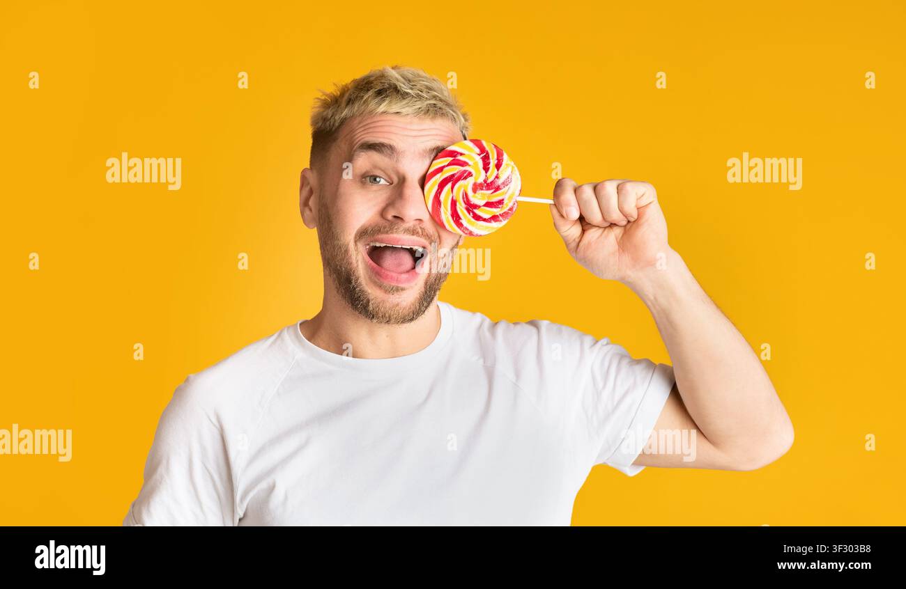 L'homme heureux ferme l'œil avec la lollipop arc-en-ciel Banque D'Images