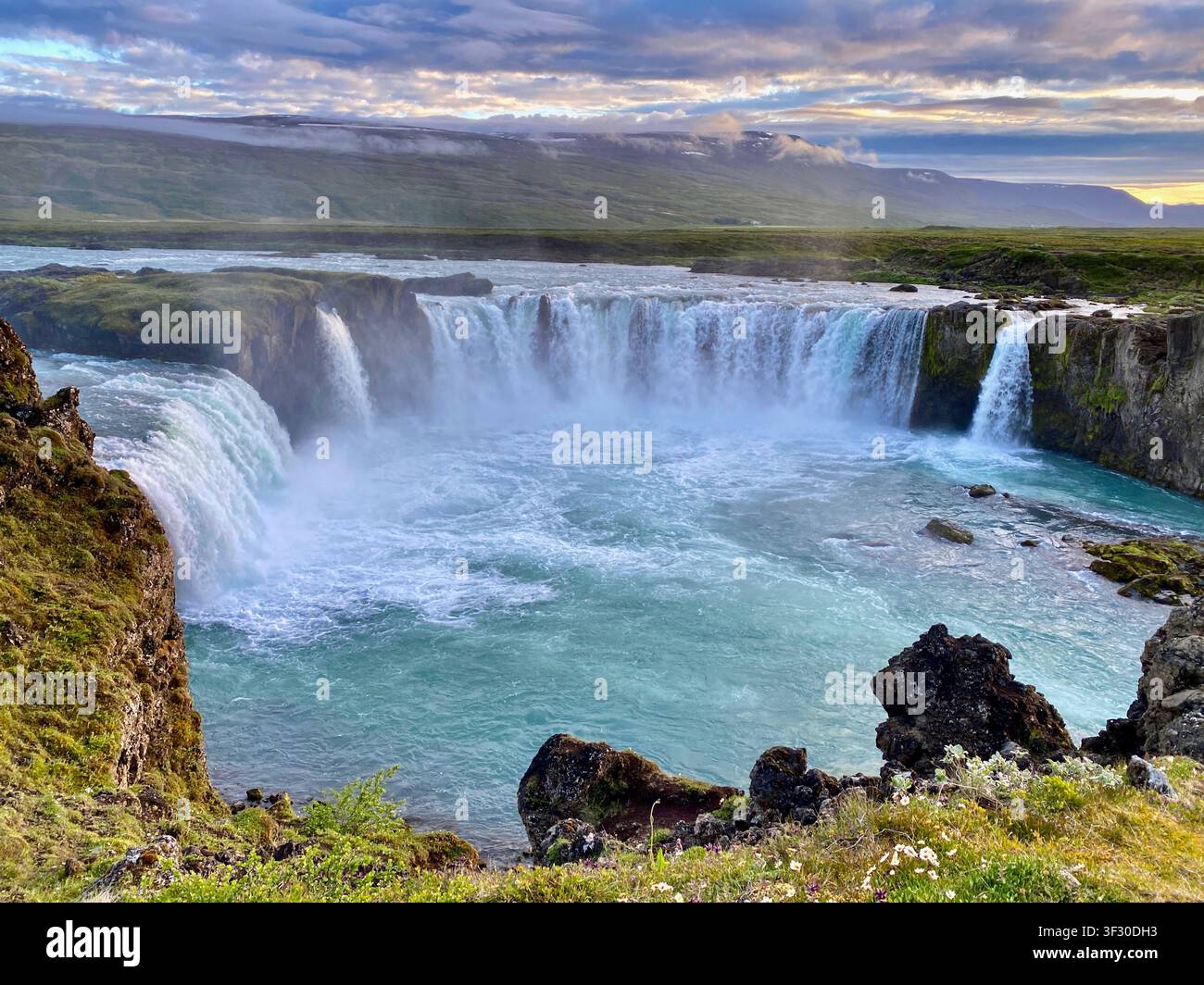 La vue panoramique puissante de la cascade de Goðafoss à l'heure dorée sous un ciel rose, Islande du Nord - Image de stock capturée avec un smartphone