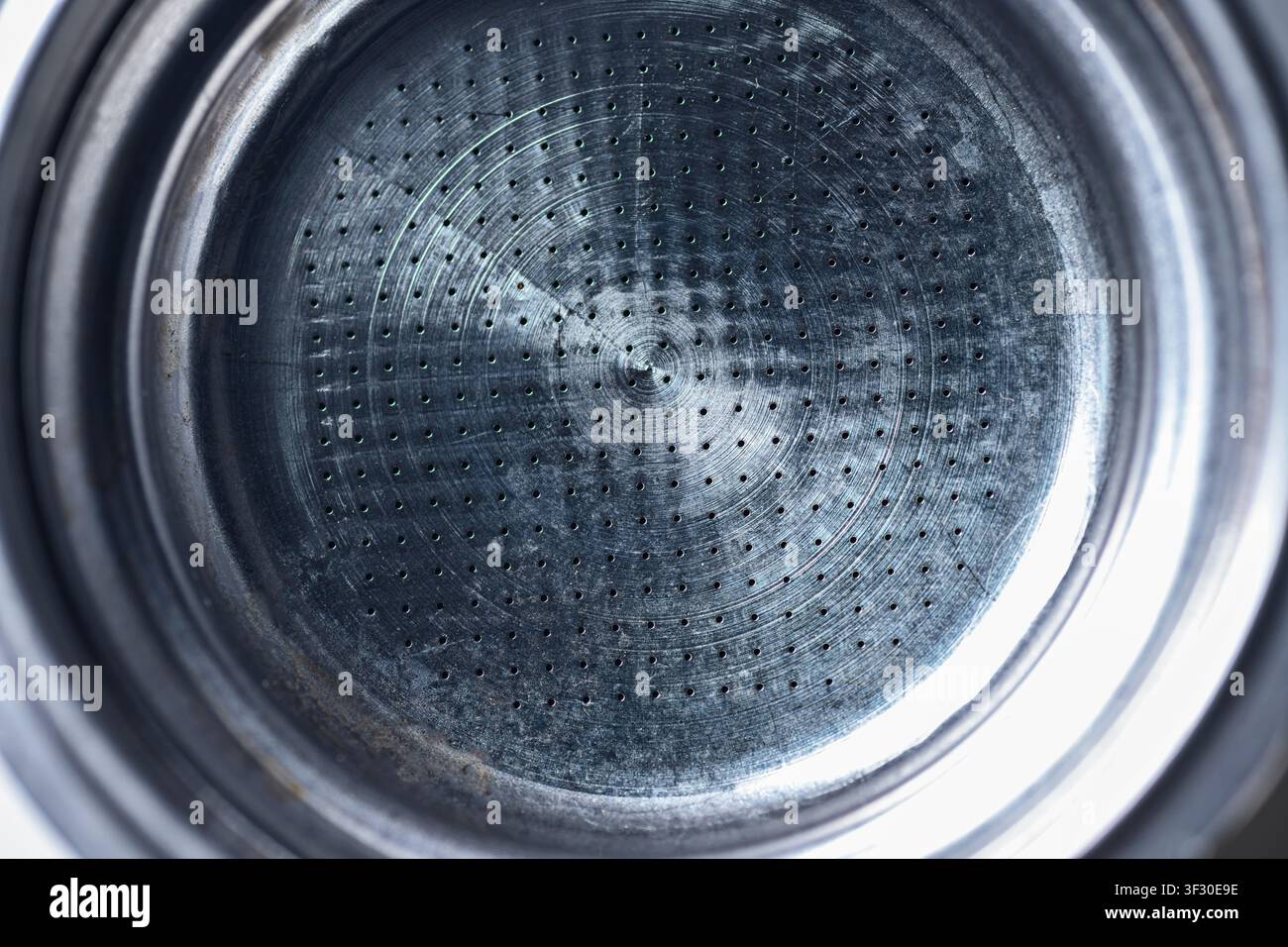 Photo macro détaillée d'un panier portafiltre en métal d'une machine à expresso montrant le motif circulaire des trous fins et la texture en acier inoxydable brossé. Ide Banque D'Images