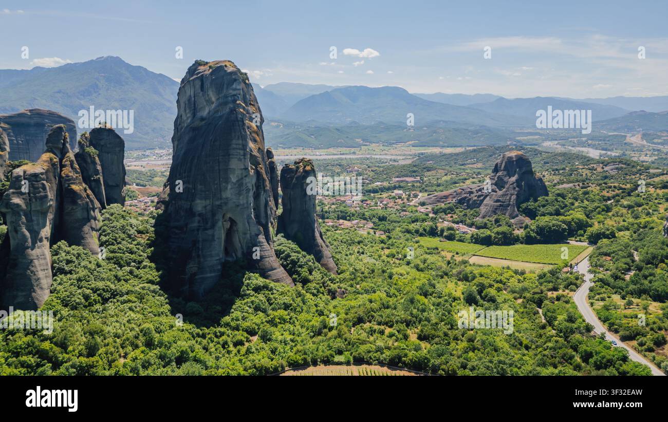 Vue par drone des massives formations rocheuses du Méteore près du village de Kastraki en Thessalie, Grèce, entourées d'une forêt verte dense par une journée d'été ensoleillée sous un ciel bleu Banque D'Images