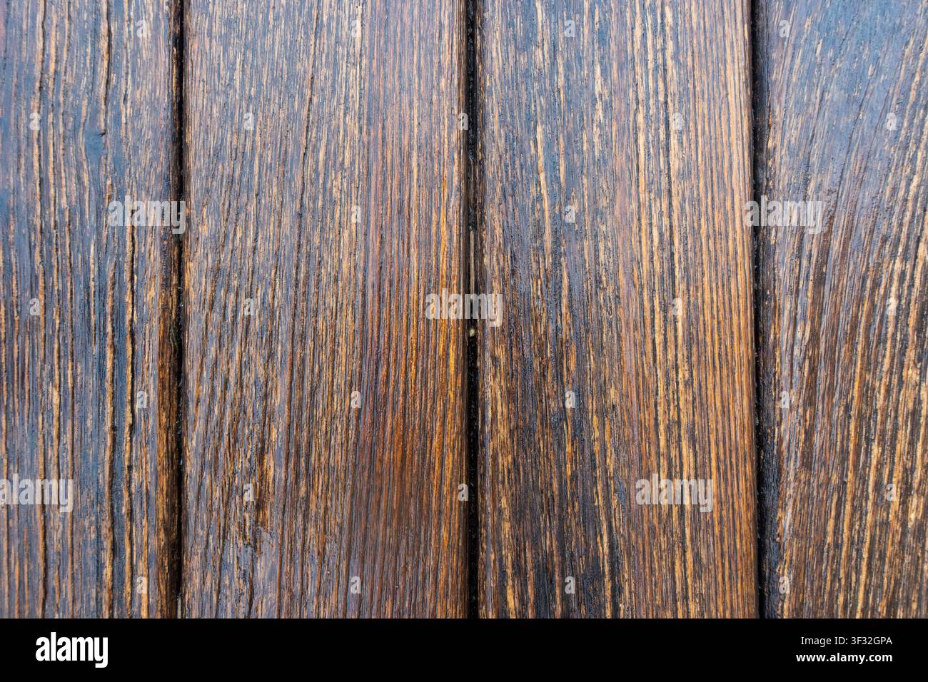 Close-up de planches de bois brun usées avec une veinure prononcée, des rainures et des vides sombres formant un fond rustique. Banque D'Images