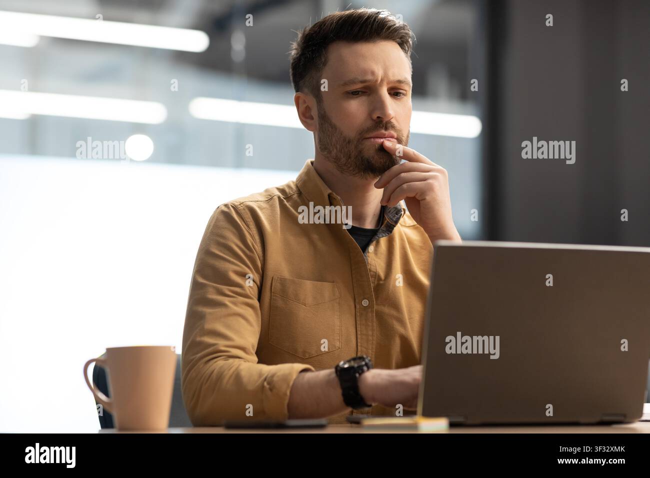 Homme caucasien ciblé travaillant sur ordinateur portable dans le bureau moderne, concept d'entreprise Banque D'Images
