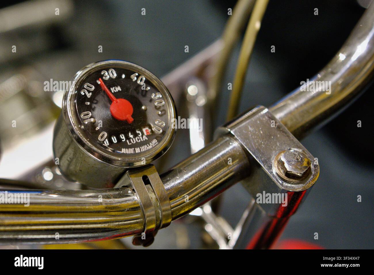 Grossissement d'un compteur de vitesse de mobylette vintage monté sur un guidon chromé, mettant en valeur l'ingénierie classique et le design nostalgique des transports. Banque D'Images