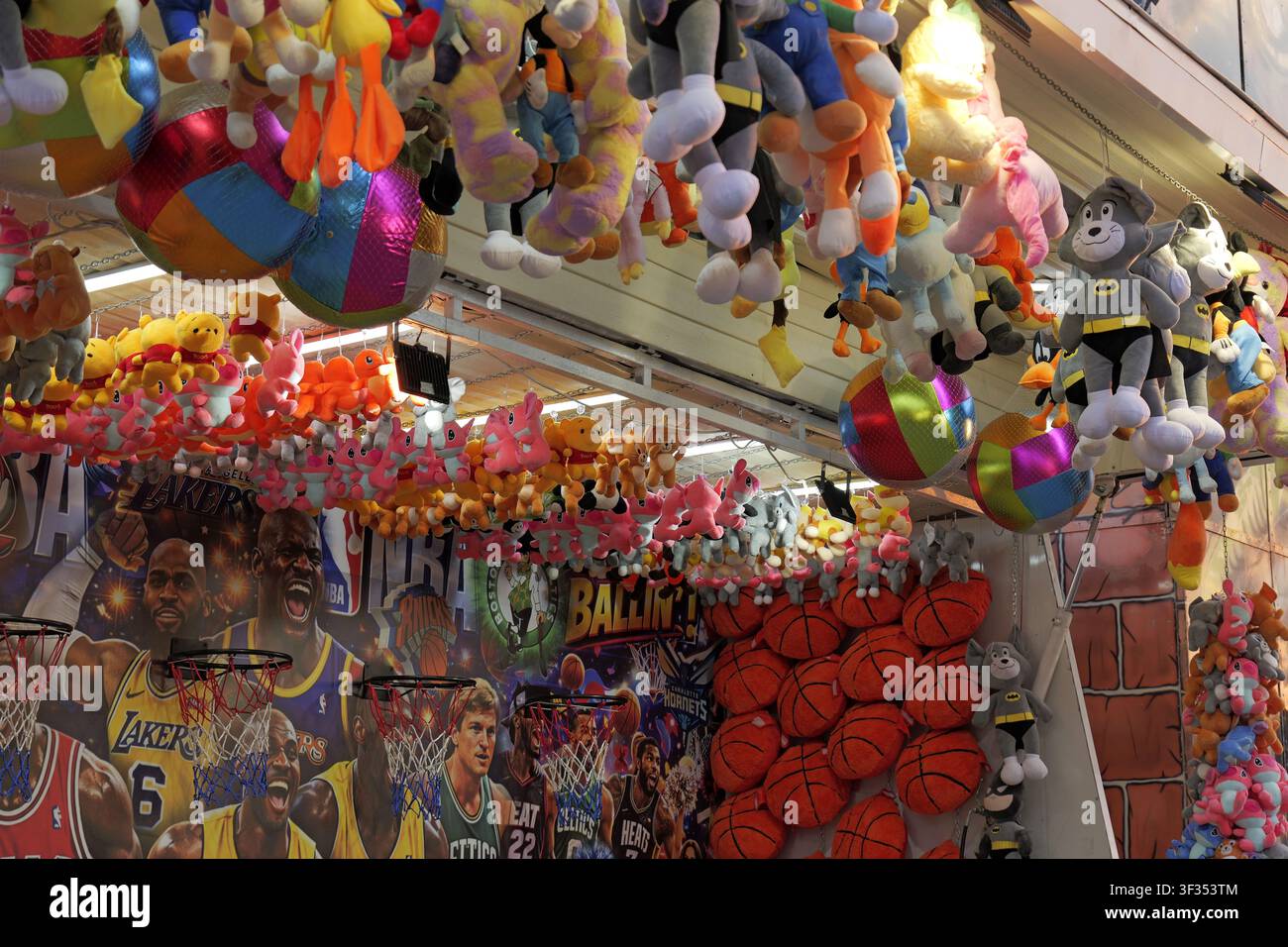 Stand de jeu de parc d'attractions affichant de nombreux jouets en peluche colorés comme prix, avec des paniers de basket sur un fond thématique NBA. Bulgarie, Varna, 20 ju Banque D'Images