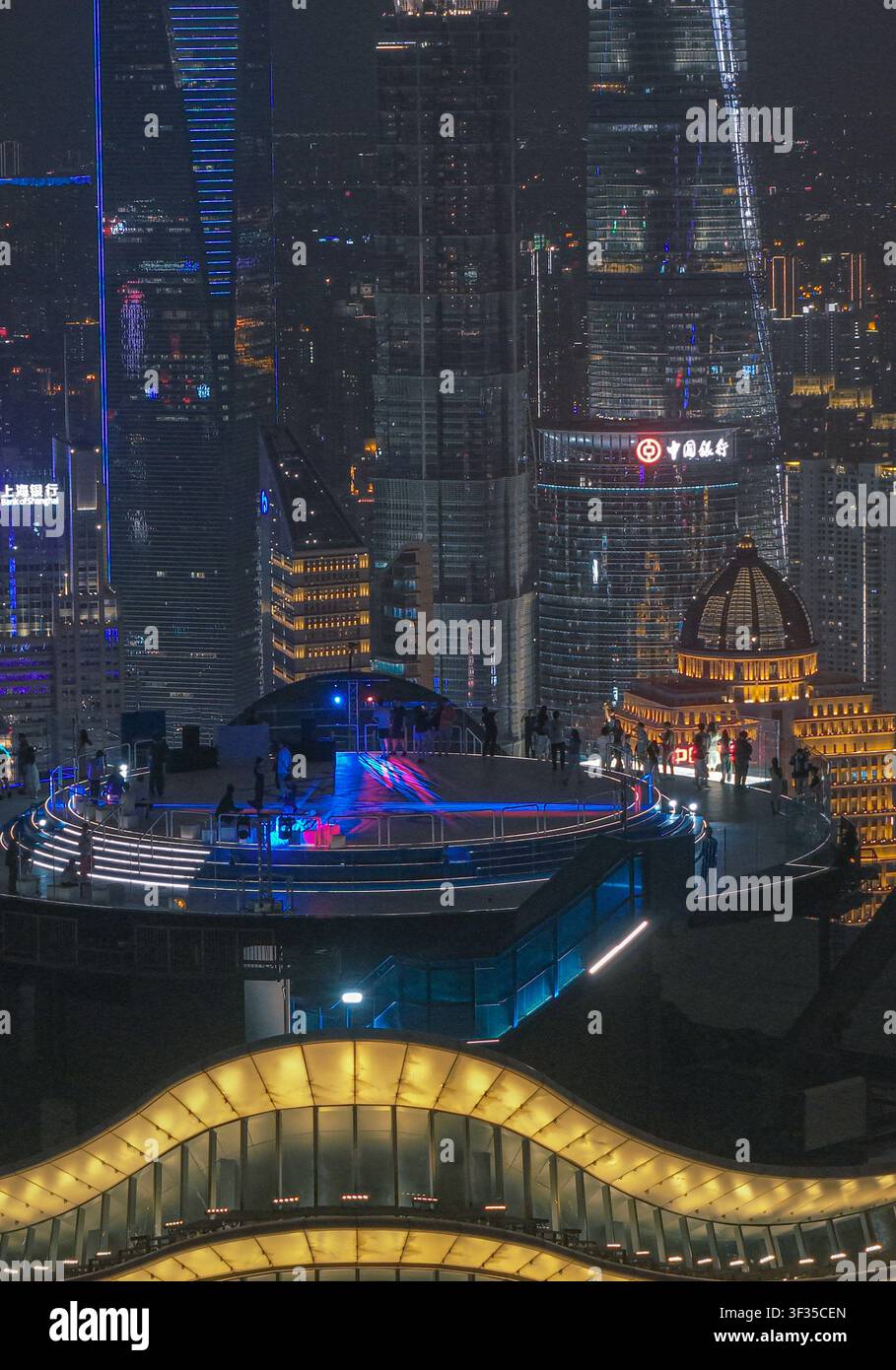 Vue aérienne du pont d'observation illuminé du Shanghai Baiyulan Plaza avec des gens profitant de la skyline nocturne de Shanghai, Shanghai, Chine. Banque D'Images