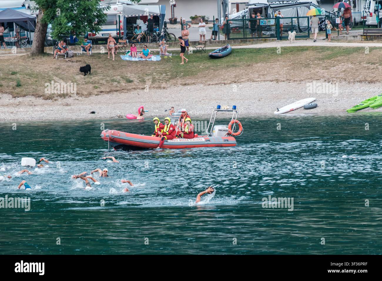 Les nageurs rivalisent d'adresse aux côtés d'un bateau de sécurité lors de la journée de test du Ledro SwimRun sur le lac Ledro, en Italie. L'événement est étroitement surveillé. Banque D'Images