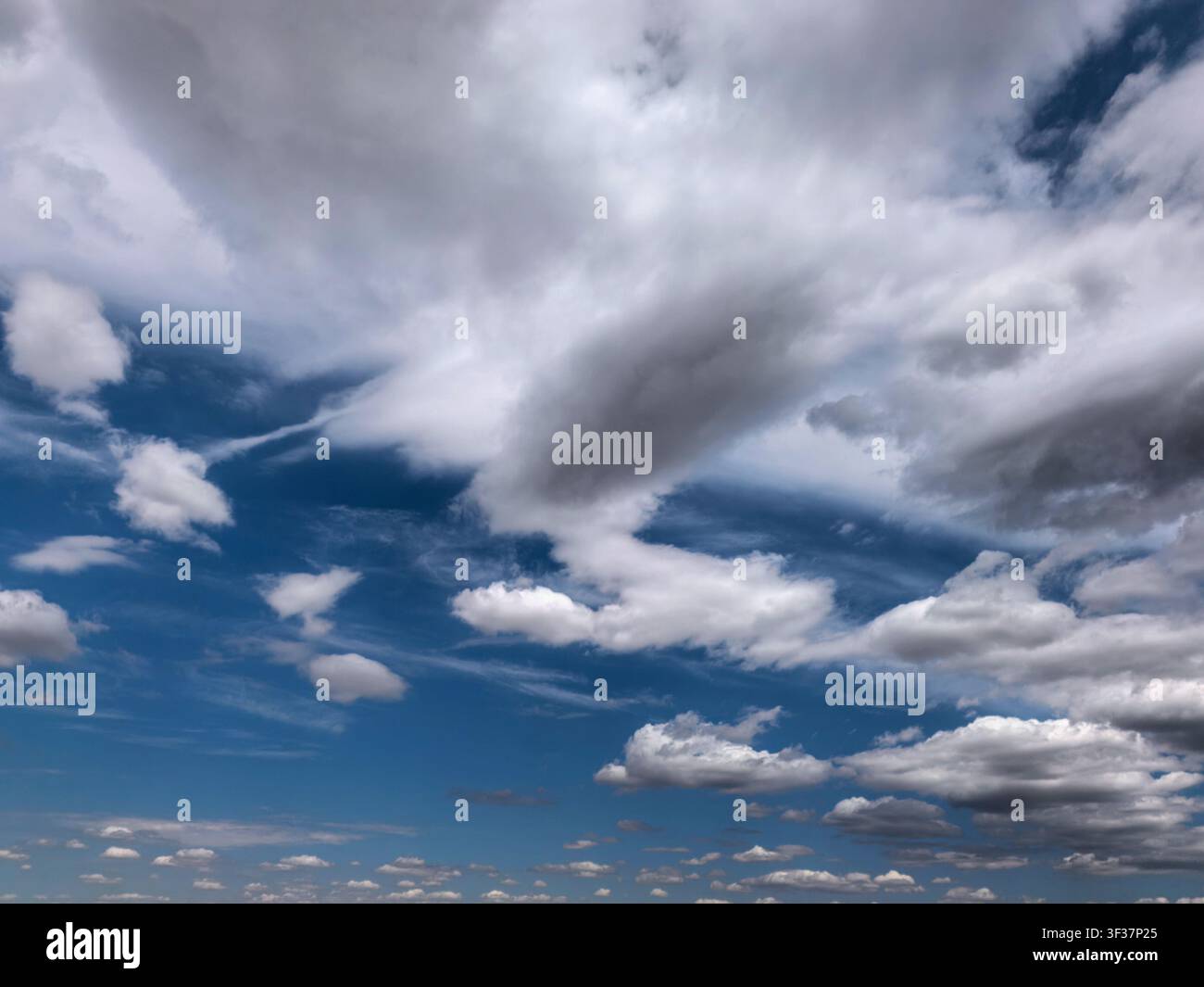 Vue panoramique de nuages cumulus et cirrus superposés dérivant dans un ciel bleu vif. Fond météorologique atmosphérique avec des formations nuageuses naturelles dramatiques Banque D'Images