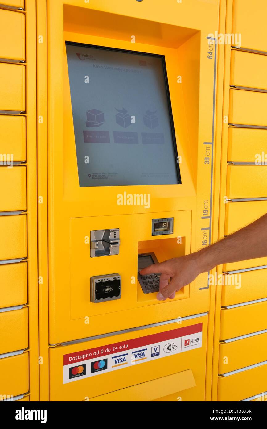 Un homme utilisant l'interface tactile d'un terminal jaune de casier de colis Paket24, avec des options pour récupérer ou envoyer un colis, à Rijeka. Banque D'Images