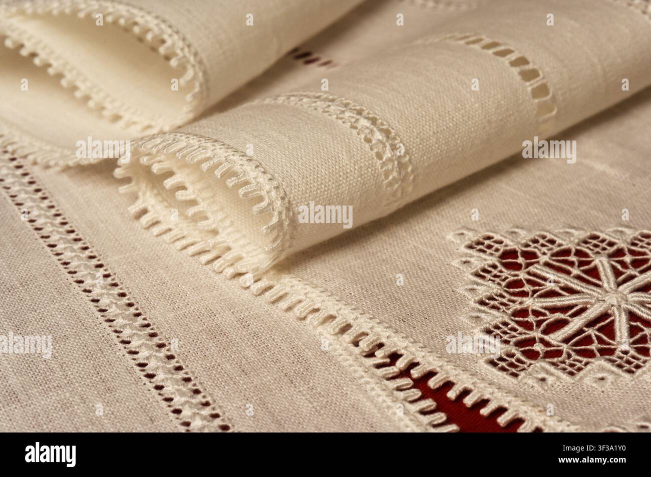 Une photographie en gros plan de textiles de table en lin vintage élégants présentant une broderie au point de fil tiré artisanale complexe et une dentelle au besoin. Le soigneusement plié Banque D'Images