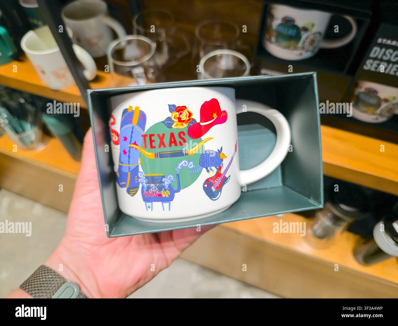 DALLAS, TX, USA - 13 JUIN 2026 : Une tasse à café sur le thème du Texas est exposée dans un magasin de détail à Dallas. La tasse présente des illustrations colorées incluant Banque D'Images