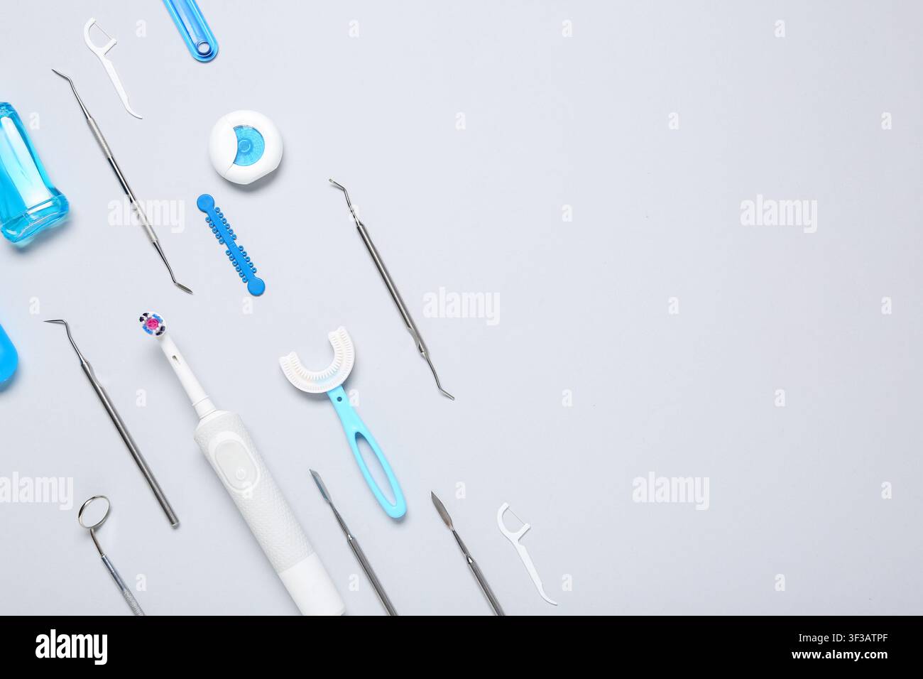 Outils de soins dentaires et produits d'hygiène buccale comprenant une brosse à dents électrique et du fil dentaire sur un fond gris clair Banque D'Images