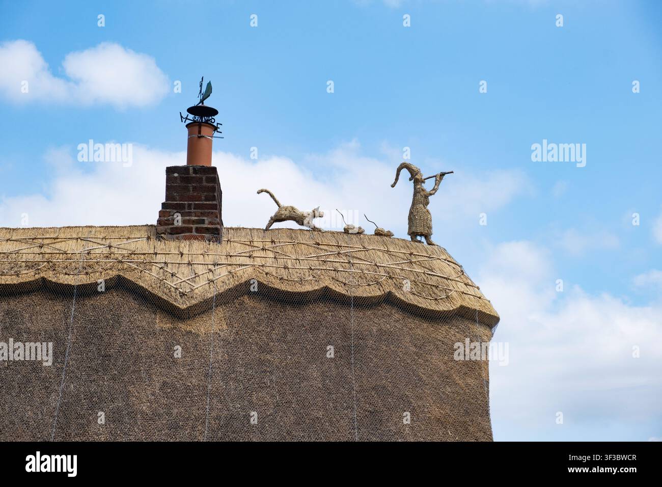 Des finials décoratifs du Pied Piper ornent la crête d’un toit de chaume neuf sur un cottage dans le Worcestershire, en Angleterre. Banque D'Images