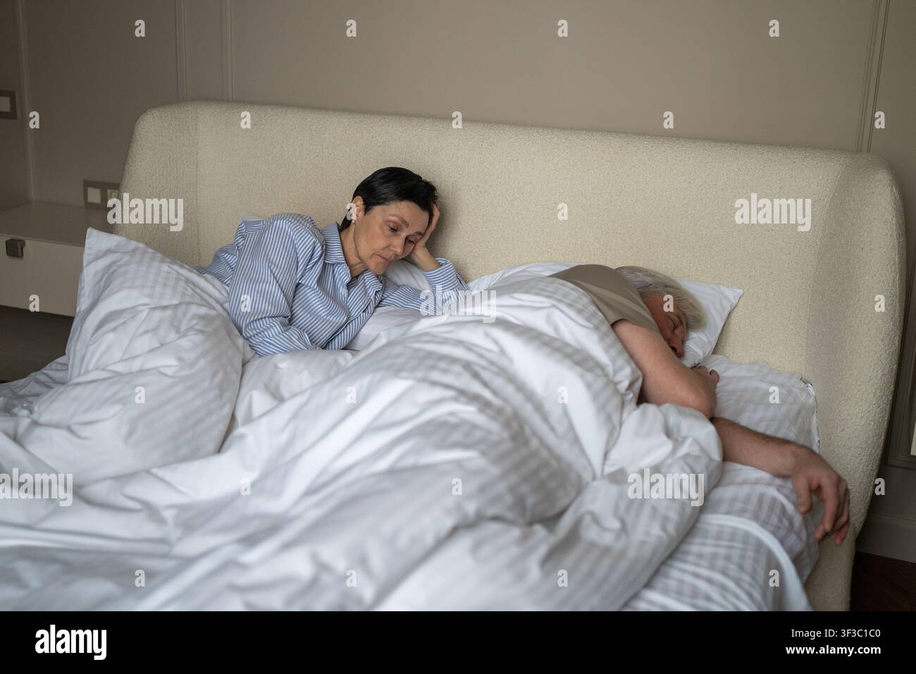 Femme âgée déprimée luttant contre les bruits de ronflement forts de son mari et perdant le sommeil la nuit. Banque D'Images
