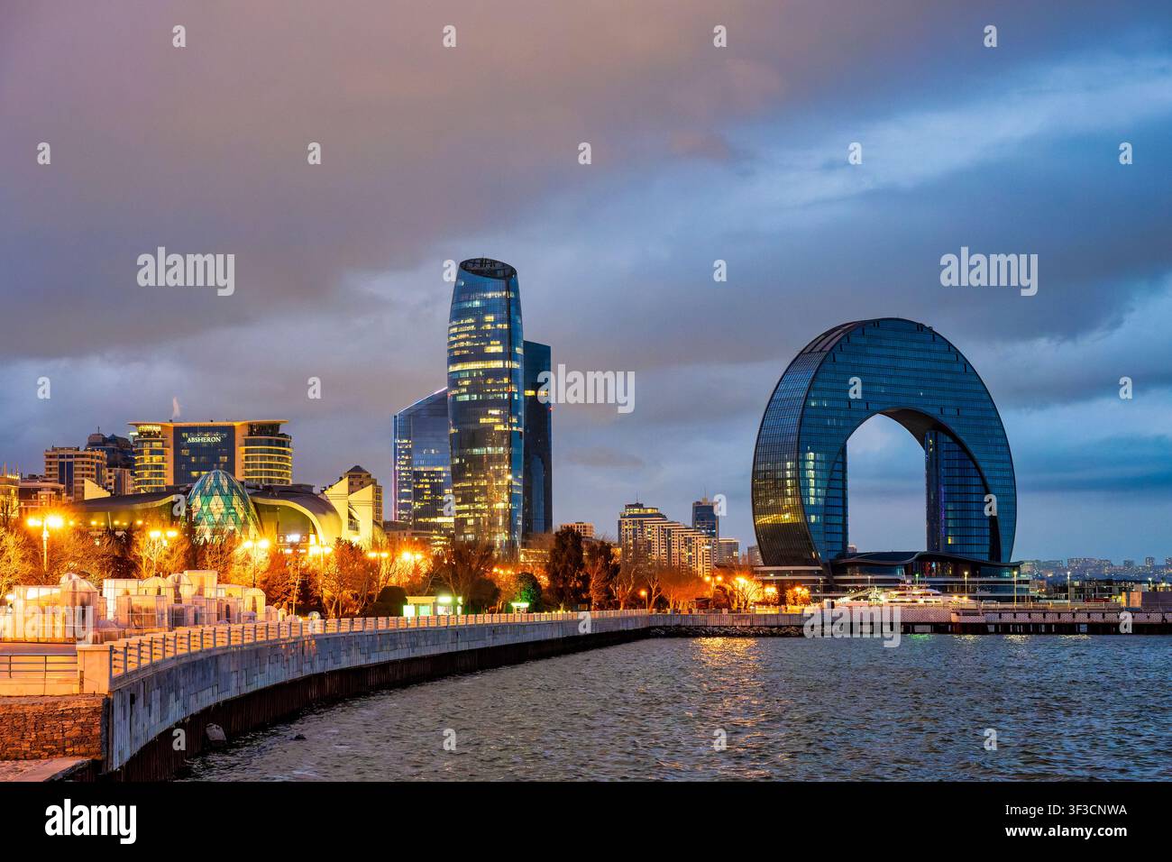 Promenade du boulevard de Bakou au bord de l'eau la nuit avec la tour Port Baku 2 et l'hôtel Crescent reflétés sur la mer Caspienne. Bakou, Azerbaïdjan. Banque D'Images