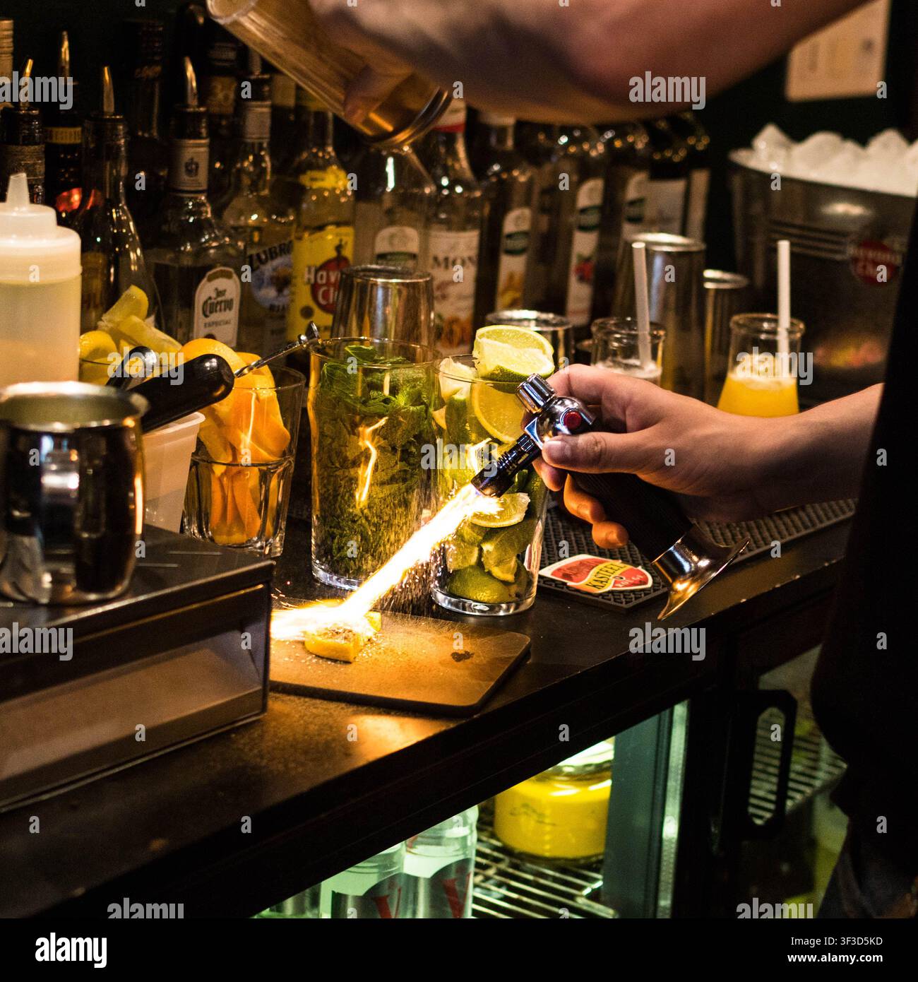 Garniture d'agrumes flambée pour la préparation de cocktails par le barman Banque D'Images