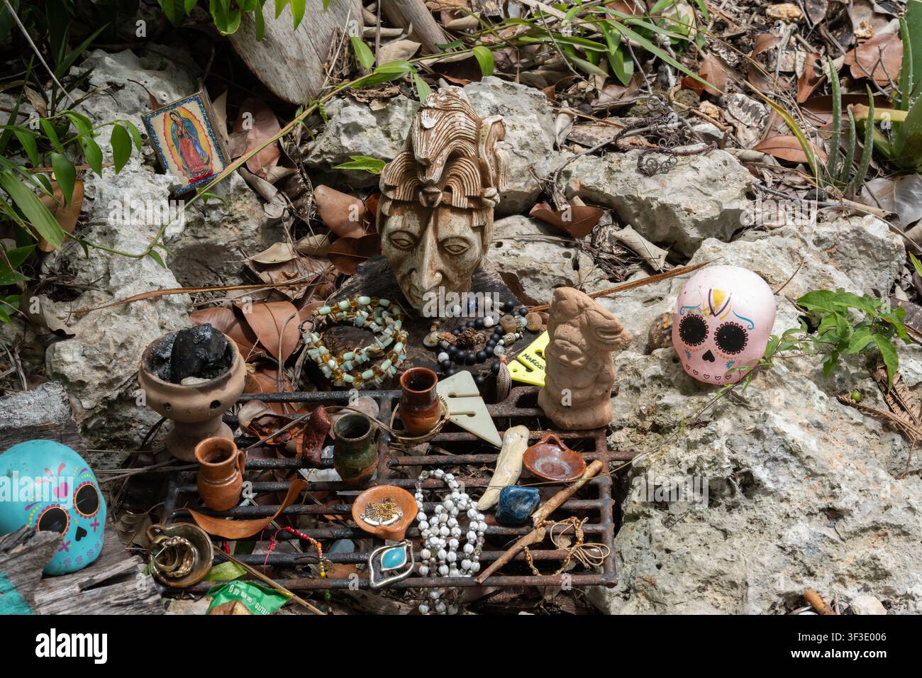 Autel affichant des offrandes, un masque maya ancien, des crânes calavera colorés et des icônes religieuses Banque D'Images