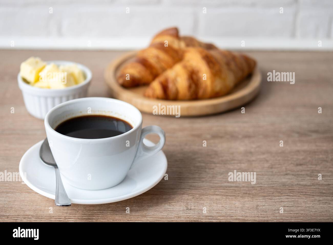 Café noir avec des croissants frais sur une table en bois Banque D'Images