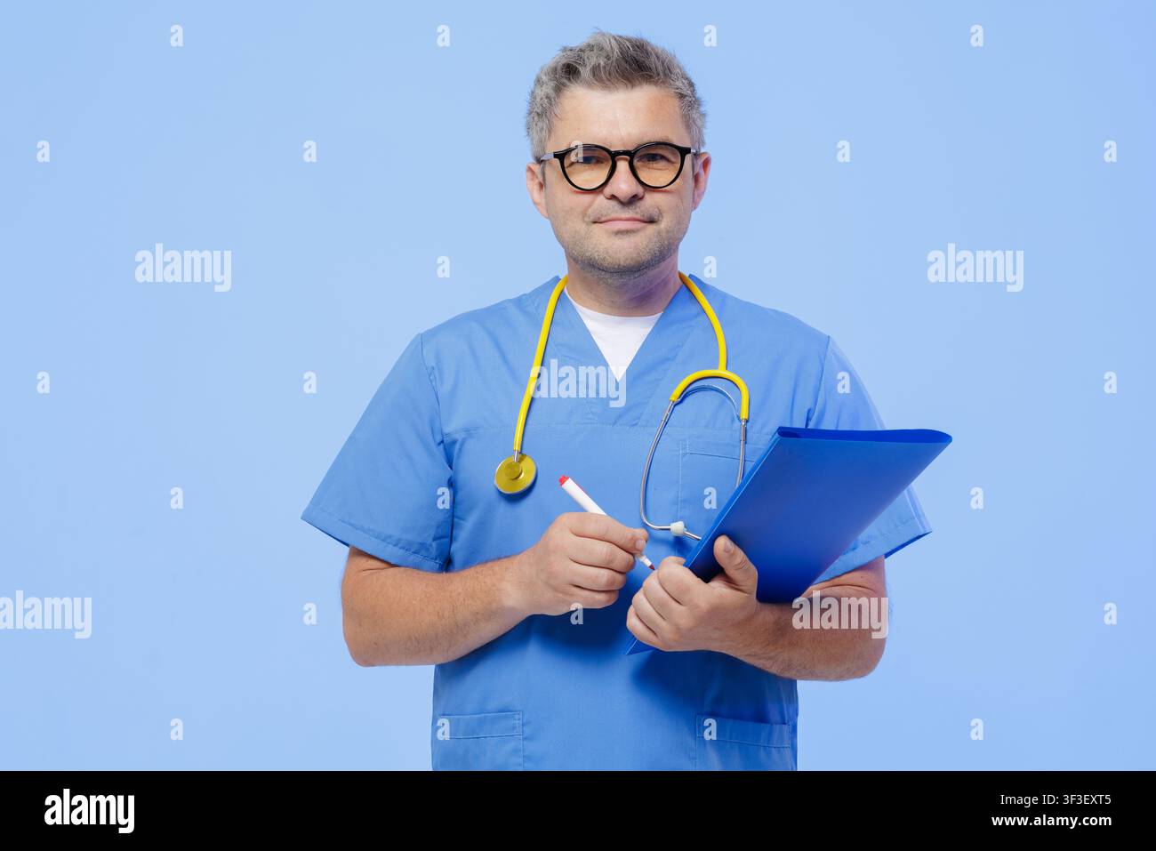 Un médecin professionnel en blouse bleue, tenant un tableau de bord et un stylo, prêt pour un rendez-vous avec un patient dans un cadre médical moderne. Banque D'Images